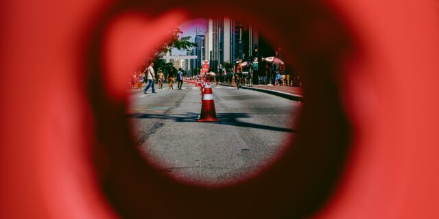 Durch ein Loch sieht man schwer erkennbar eine Strasse mit Warnpfosten.
