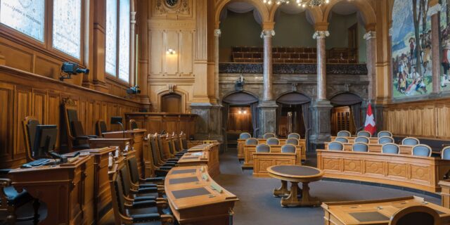Schweizer Bundeshaus von innen. Tische und Stühle, ein Landschaftsbild an der Wand.