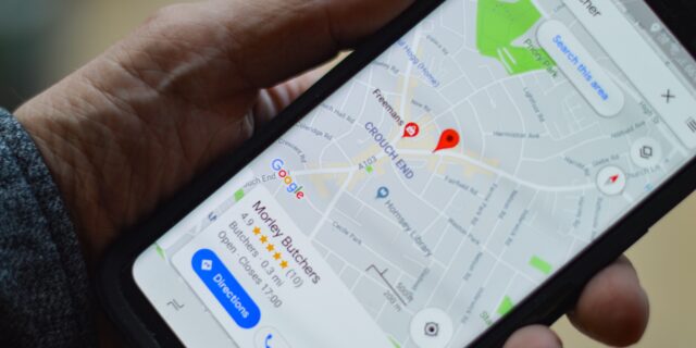 Eine person hält ein Handy in der Hand, auf dem Google Maps geöffnet ist.