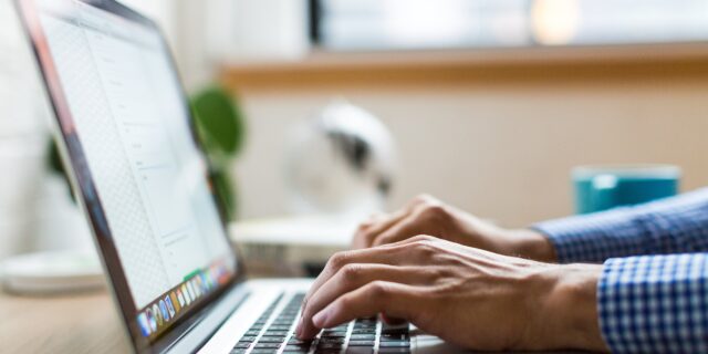 Hände, die auf einer Laptop-Tastatur tippen.