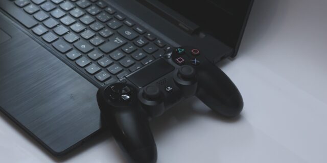 Auf einem Tisch liegen ein Laptop und eine Spielkonsole