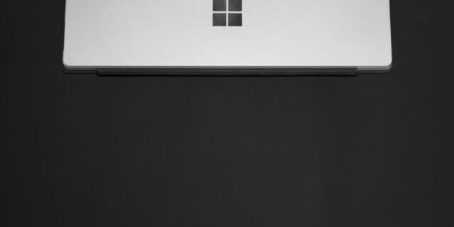 Schwarz-weiss-Bild, ein zugeklapptes Windows Notebook liegt auf einem dunklen Hintergrund.