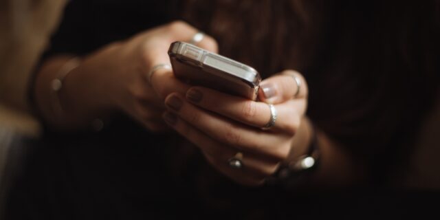 Die Hände einer Person, die ein Handy halten