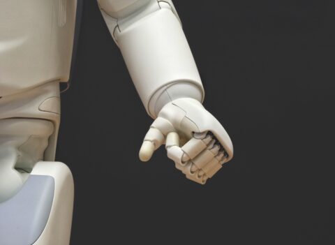 Weisse Roboterhand zu einer Faust geballt vor schwarzem Hintergrund