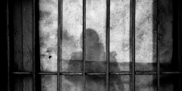 Gitterstäbe, dahinter der Schatten einer Person