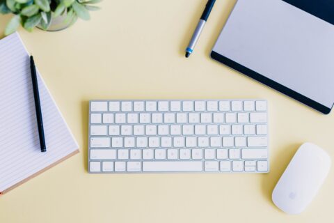 Computertastatur und Maus mit Notizblock auf Schreibtisch