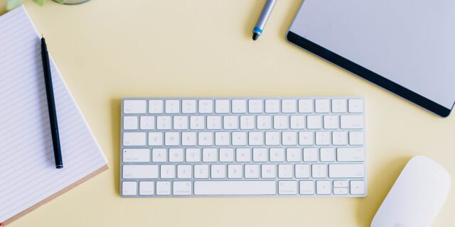 Computertastatur und Maus mit Notizblock auf Schreibtisch