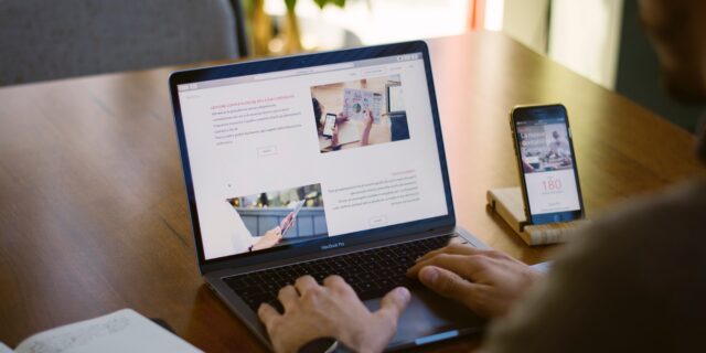 Hände einer Person über der Tastatur eines Laptops. Auf dem Bildschirm ist eine Webseite zu sehen.