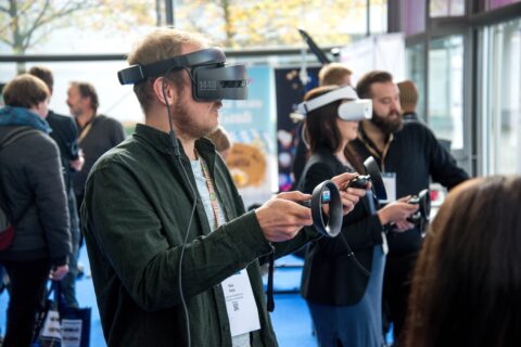 Mann mit Virtual Reality Brille auf dem Kopf und Konsole in den Händen