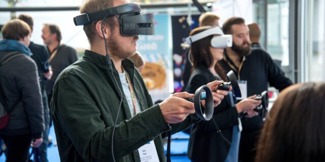 Mann mit Virtual Reality Brille auf dem Kopf und Konsole in den Händen